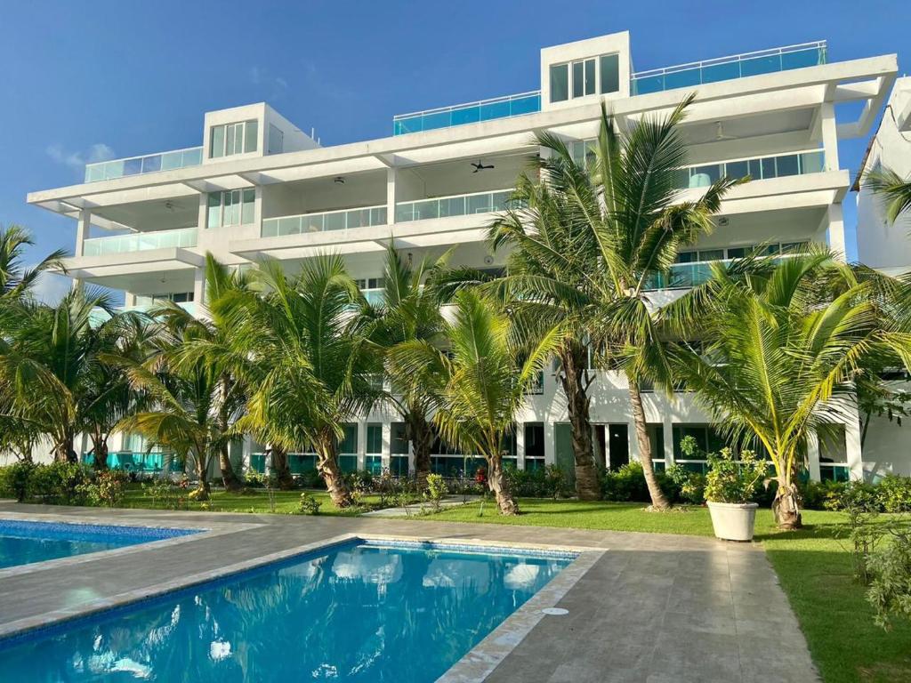 a large white building with palm trees and a swimming pool at Beautiful Two bedrooms apartment in Punta Cana