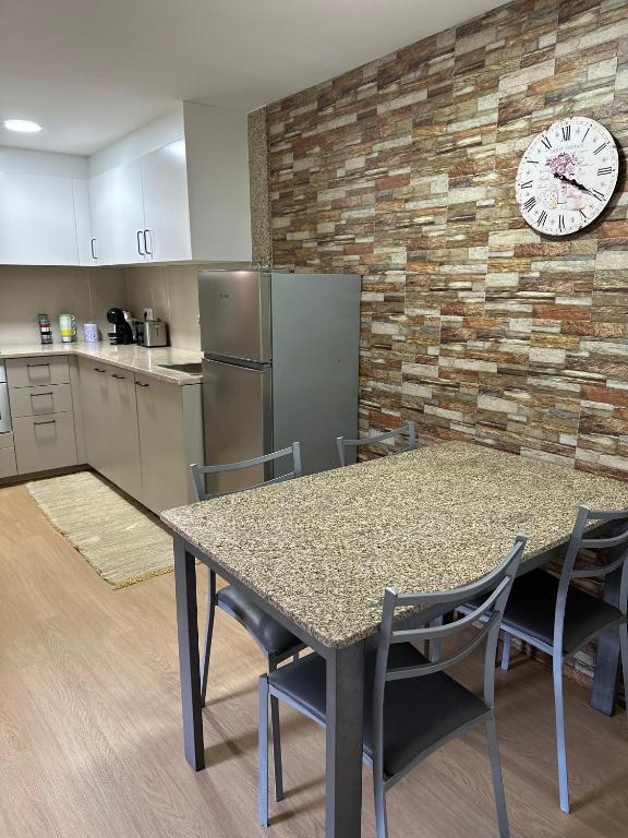 a kitchen with a table and chairs and a clock on a wall at Chalé da Fonte - T2 in Geres