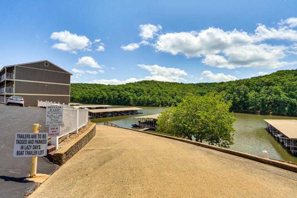 a bridge over a river with a building and a sign at Lake and Pool Access Lazy Days Condo with Balcony! in Osage Beach