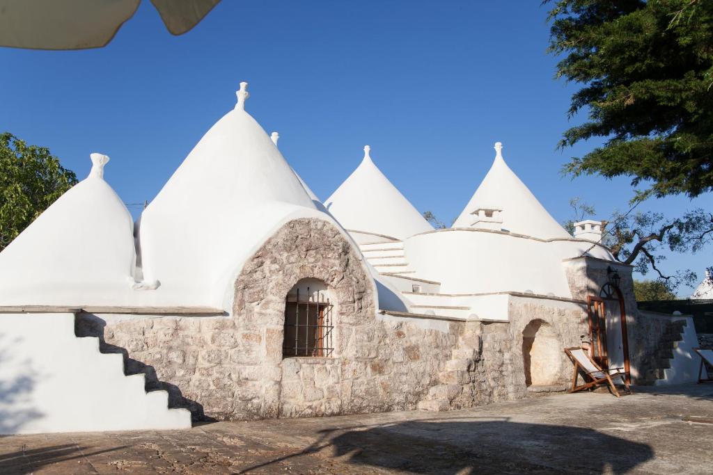 a white building with steep white roofs and stairs at Trullo Degli Ulivi in Ostuni