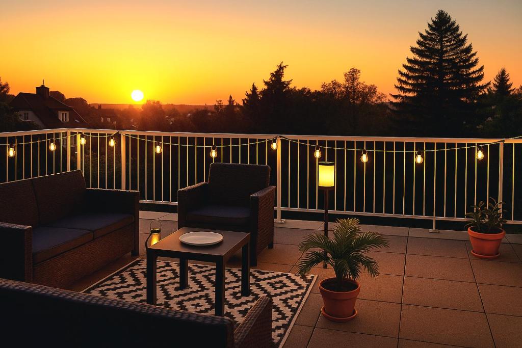 a sunset on a balcony with a couch and a table at Skylight46 La Terrasse St Louis in Saint-Louis
