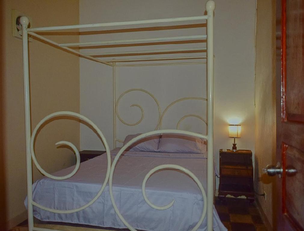 a white canopy bed with a white frame in a bedroom at Casa Oasis Colonial in El Venado