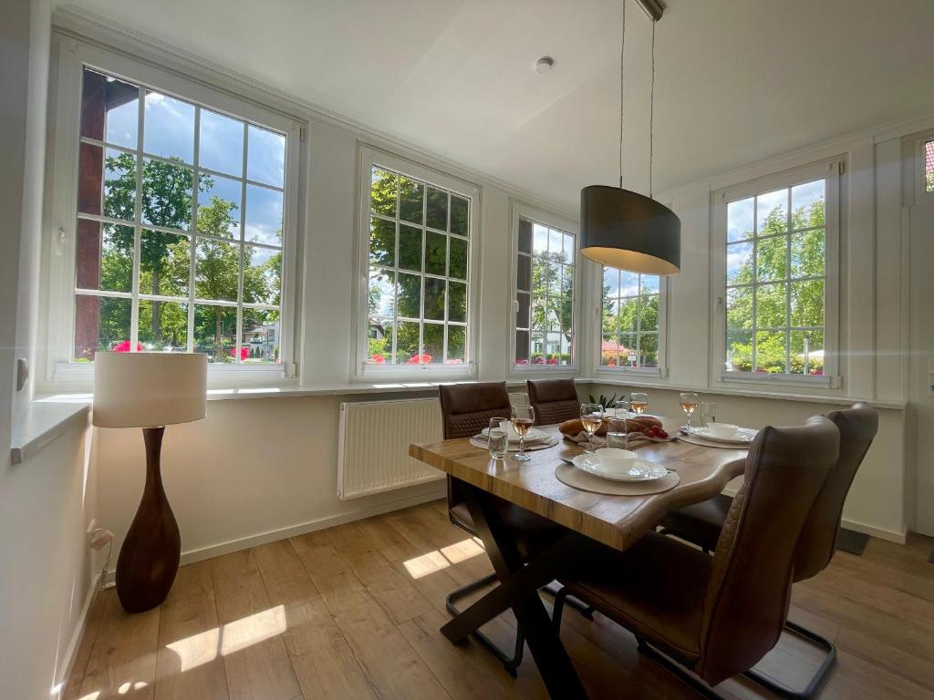 a dining room with a table and chairs and windows at Brot & Auszeit in Falkensee