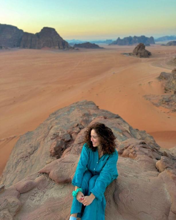 a woman sitting on a rock in the desert at Kadi Wadi Rum in Al Jafr