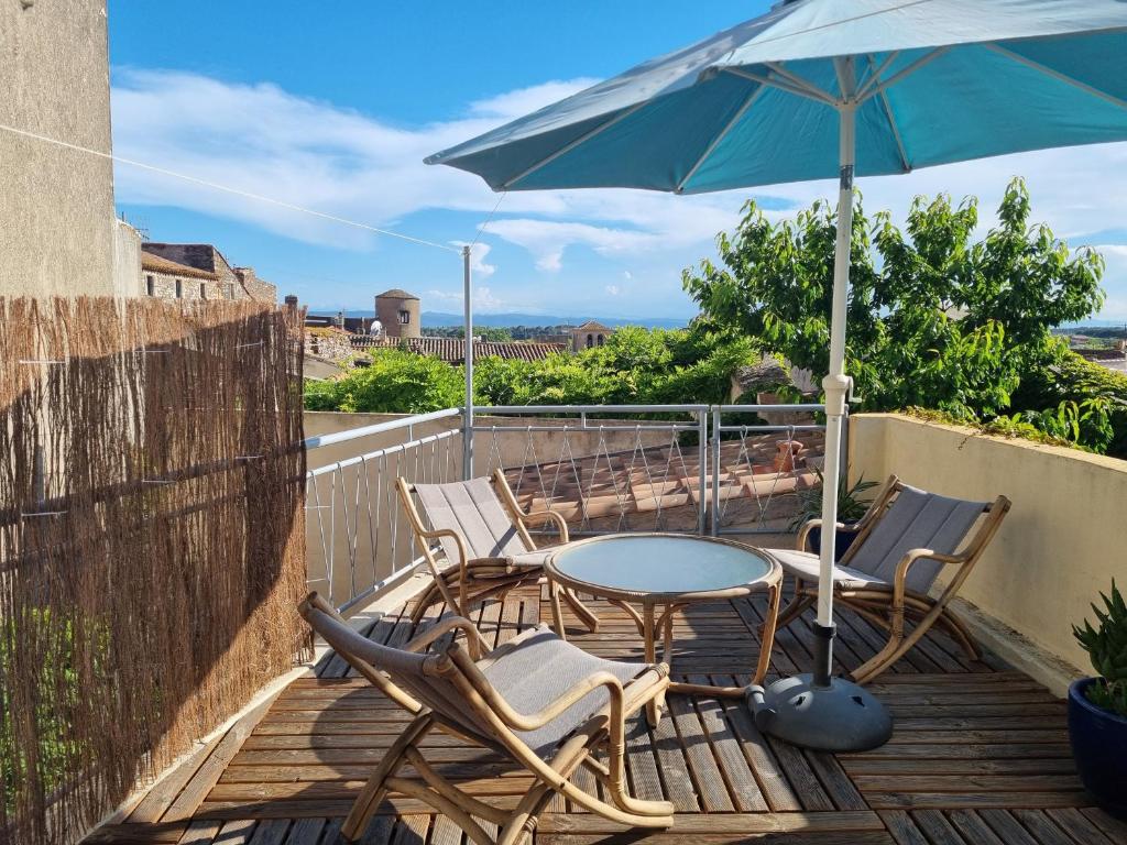 un patio avec des chaises, une table et un parasol dans l'établissement Maison de charme, à Caunes-Minervois