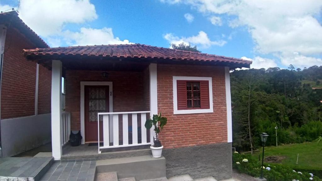 a small red brick house with a porch at Pousada Pedacinho do Ceu- chalé 1 in Cunha
