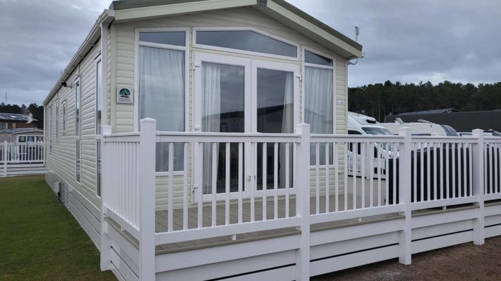 a tiny house with a white fence at Northern Light Villa, forest, beach and bubbles in Burghead