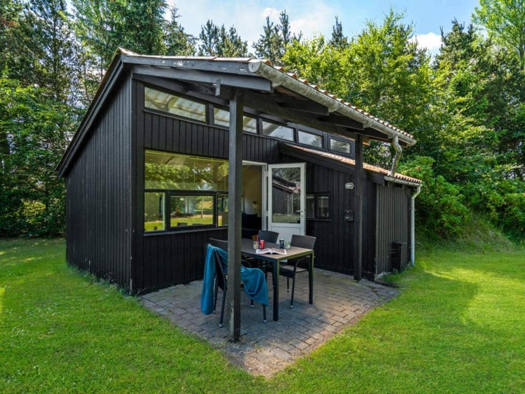 a black shed with a table in the grass at 4 person holiday home in Hampen in Hampen