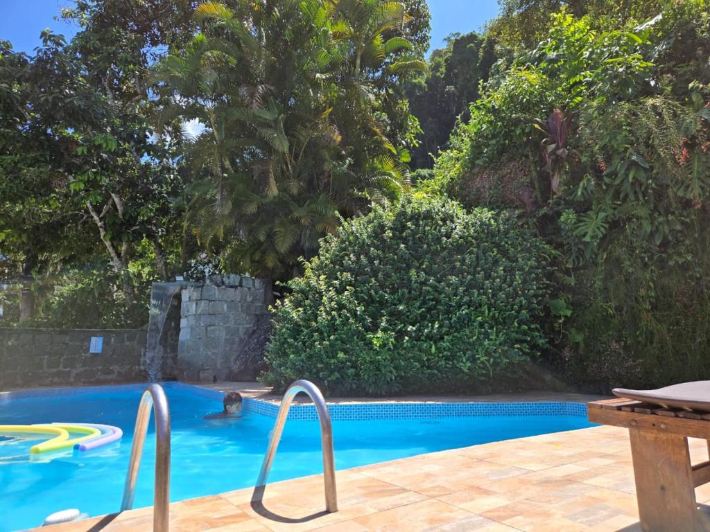 a swimming pool with two metal rails in a yard at Apartamentos Casa da Pedra in Ubatuba