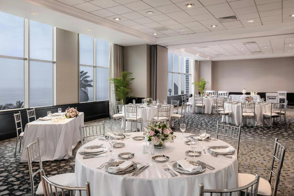 einen Bankettsaal mit weißen Tischen, Stühlen und Fenstern in der Unterkunft JW Marriott Hotel Lima in Lima