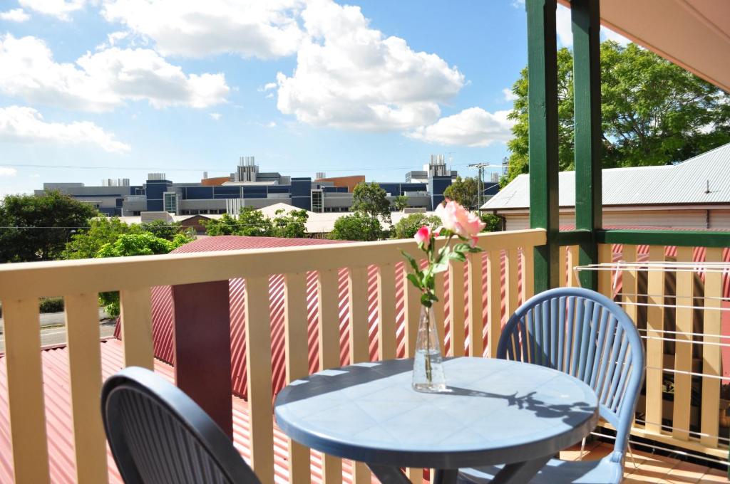 a table on a balcony with a vase with a flower at Isla House PA in Brisbane