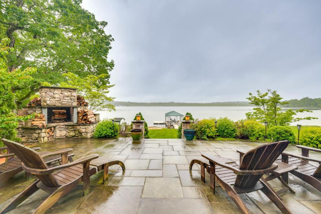 a patio with two wooden chairs and a stone fireplace at Luxe Family Home on Orange Lake with Private Dock! in Newburgh