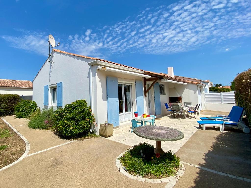 une maison avec un patio avec une table et des chaises dans l'établissement Maison 3 chambres (5 pers) à 400m de la plage avec jardin clos, parking & WIFI à Brétignolles-sur-Mer - FR-1-231-323, à Bretignolles-sur-Mer