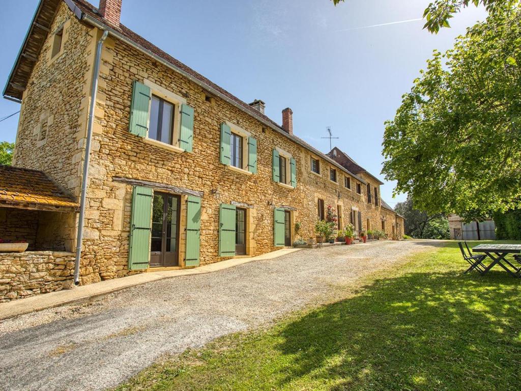 a stone building with green doors and a picnic table in front at Maison au calme avec jardin, proche de Sarlat - Idéale pour familles et activités en plein air. - FR-1-616-295 in Carlux