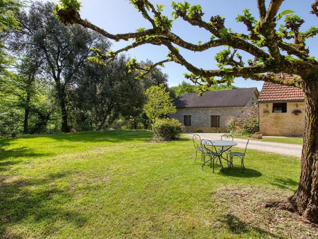 a table and chairs in the yard of a house at Charmant gîte avec jardin, clim, wifi, proche Sarlat et rivière Dordogne, animaux bienvenus - FR-1-616-310 in Carlux