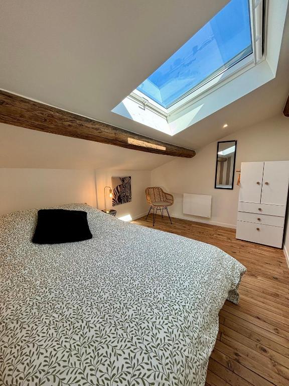 a bedroom with a large bed and a skylight at Appartement 2 personnes - Centre ville in Saint-Dizier