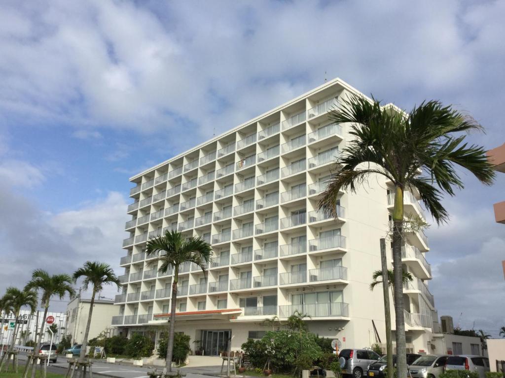 un gran edificio blanco con palmeras delante en Hotel Gran View Garden Okinawa, en Tomigusuku