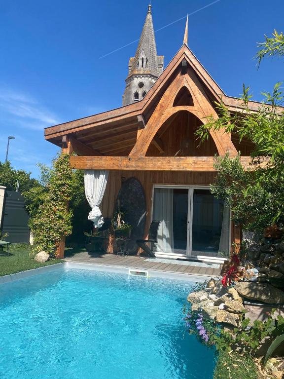 une maison avec une piscine devant une maison dans l'établissement Chalet Atypique VUE Piscine Chauffée, à Gujan-Mestras