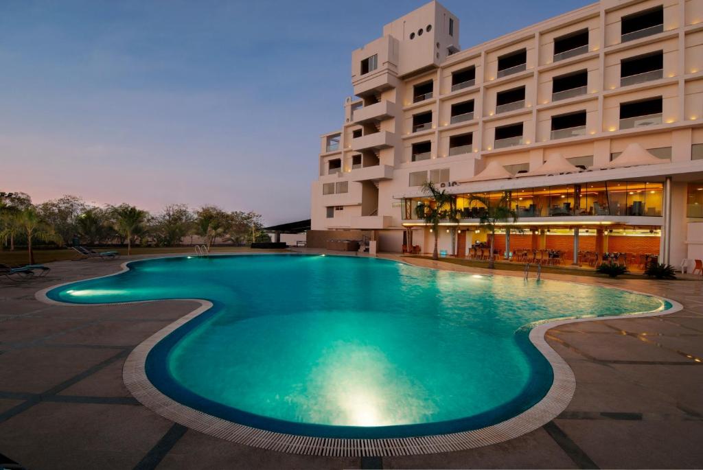 a swimming pool in front of a building at Seasons Rajkot in Rajkot