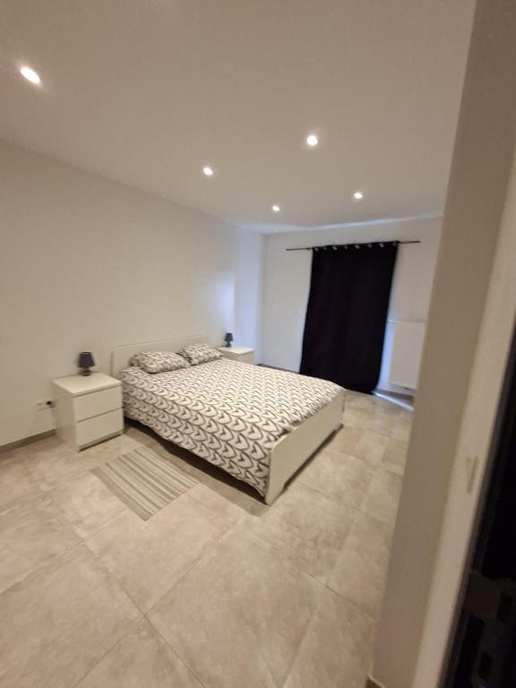 a white bedroom with a bed and a night stand at Le Franchet in Dinant