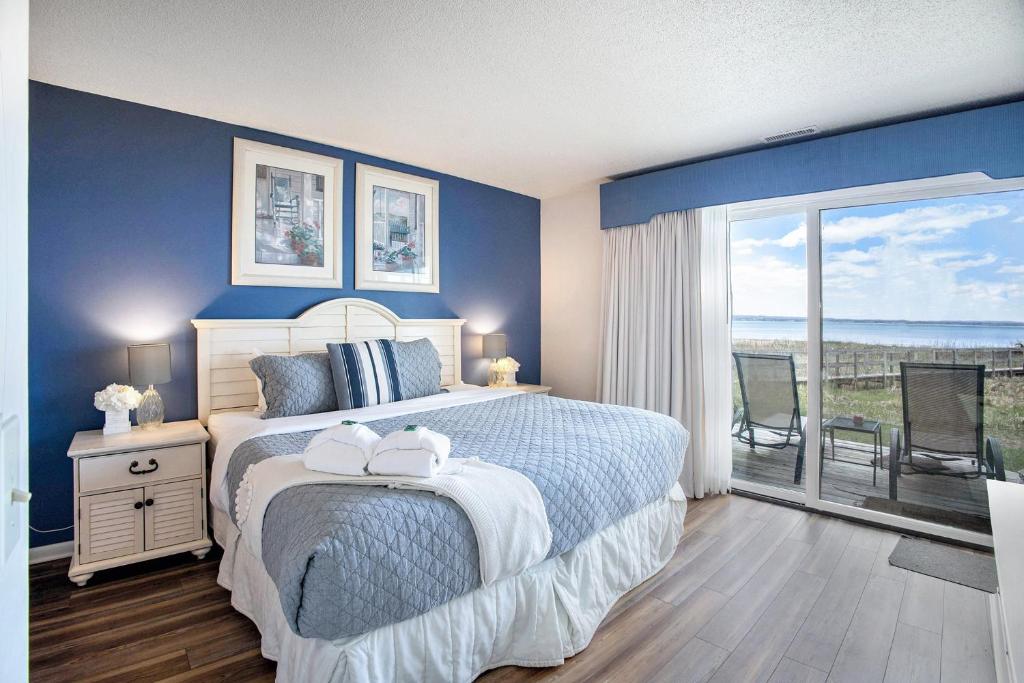 a bedroom with a bed with blue walls and a balcony at Gorgeous Lake View Deluxe Condo at The Shores in Traverse City