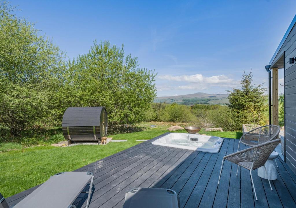 een terras met stoelen en een vuurplaats op een huis bij Deer Cottage in Eldroth