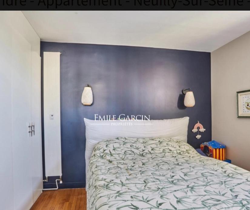 - une chambre dotée d'un lit avec un mur bleu dans l'établissement Pont de neuilly, à Neuilly-sur-Seine