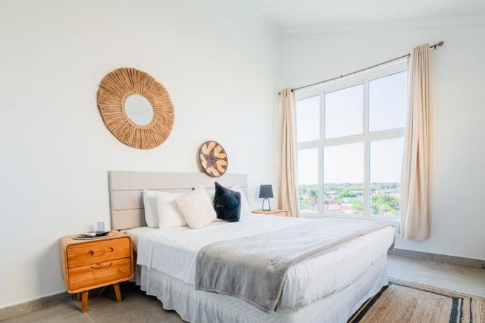 a white bedroom with a large bed and a window at Arubas Life 408 in Noord