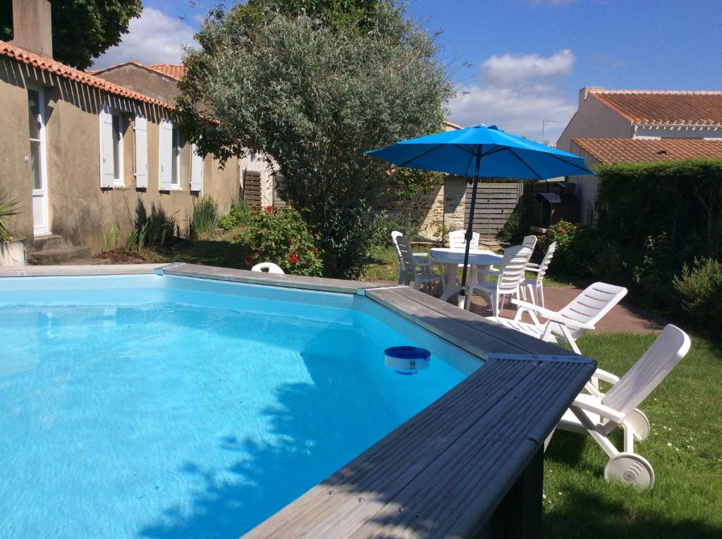 une piscine avec une table, des chaises et un parasol dans l'établissement Charmante maison dans le centre d'Olonne sur mer, à Les Sables-dʼOlonne