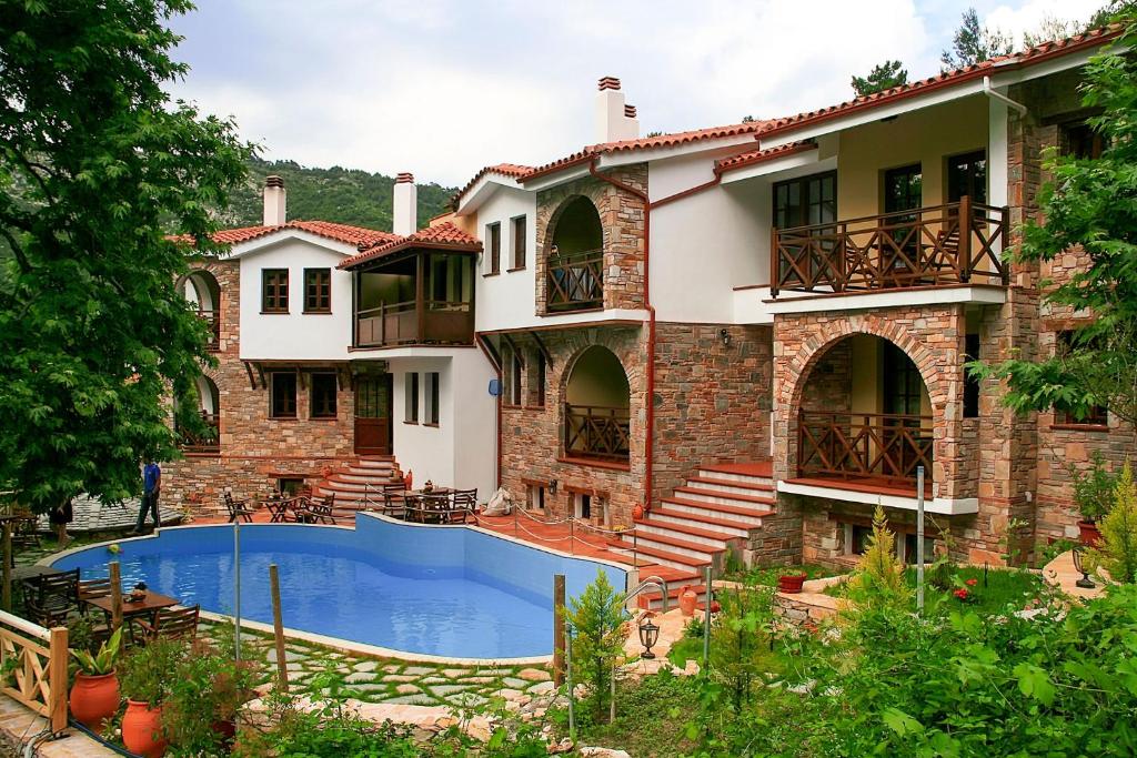 a large house with a swimming pool in front of it at Kazaviti Luxury Suites in Mikrós Prínos