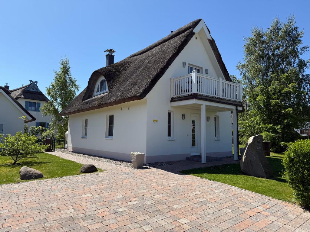 una casa bianca con balcone su un vialetto in mattoni di Reethaus Sonnenwiese, Haus am Meer mit eingezäuntem Garten, Hunde herzlich willkommen a Glowe