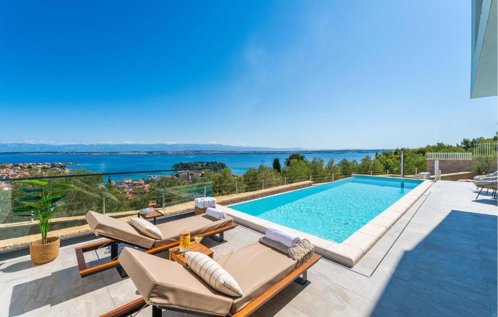 a swimming pool with chaise lounge chairs next to a swimming pool at Lovely Home In Preko With Sauna in Preko