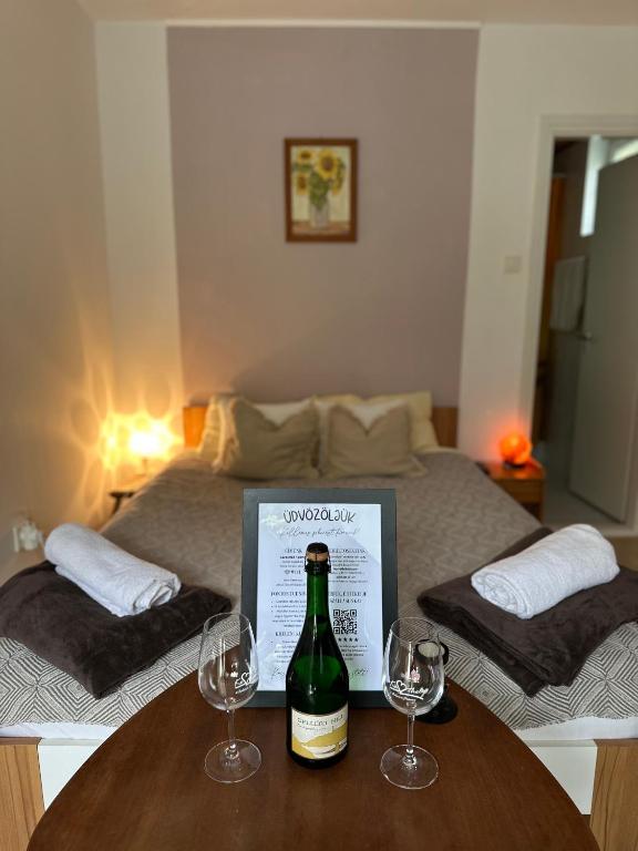 a bottle of wine on a table with two wine glasses at Sarokház Rooms in Keszthely