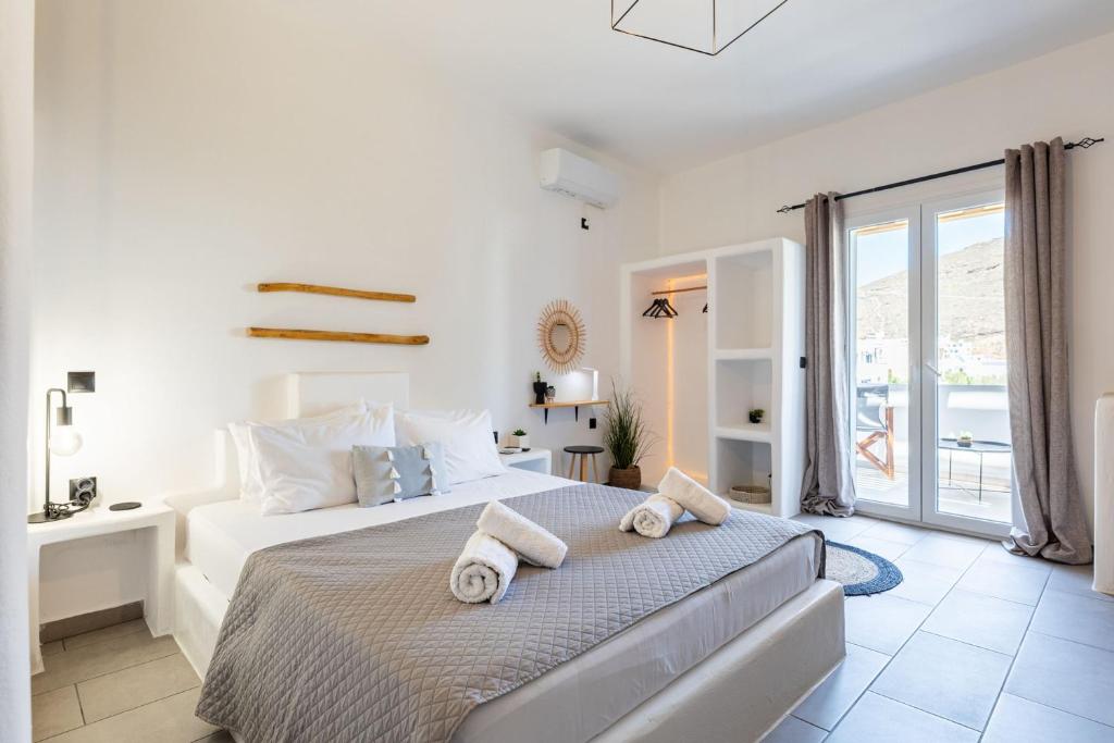 a white bedroom with a bed with towels on it at THIRAMNA Apts KYTHNOS in Mérikhas