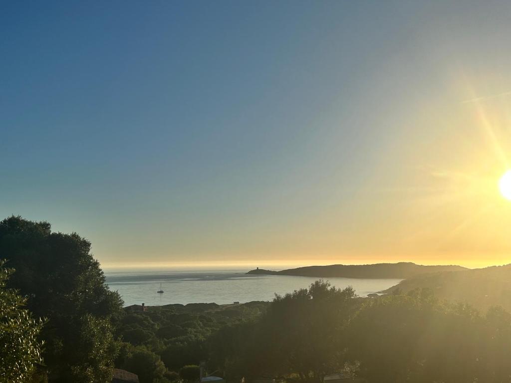 - une vue sur l'océan et le soleil au ciel dans l'établissement Appartement vue mer Vulpaghja 01, à Cargèse