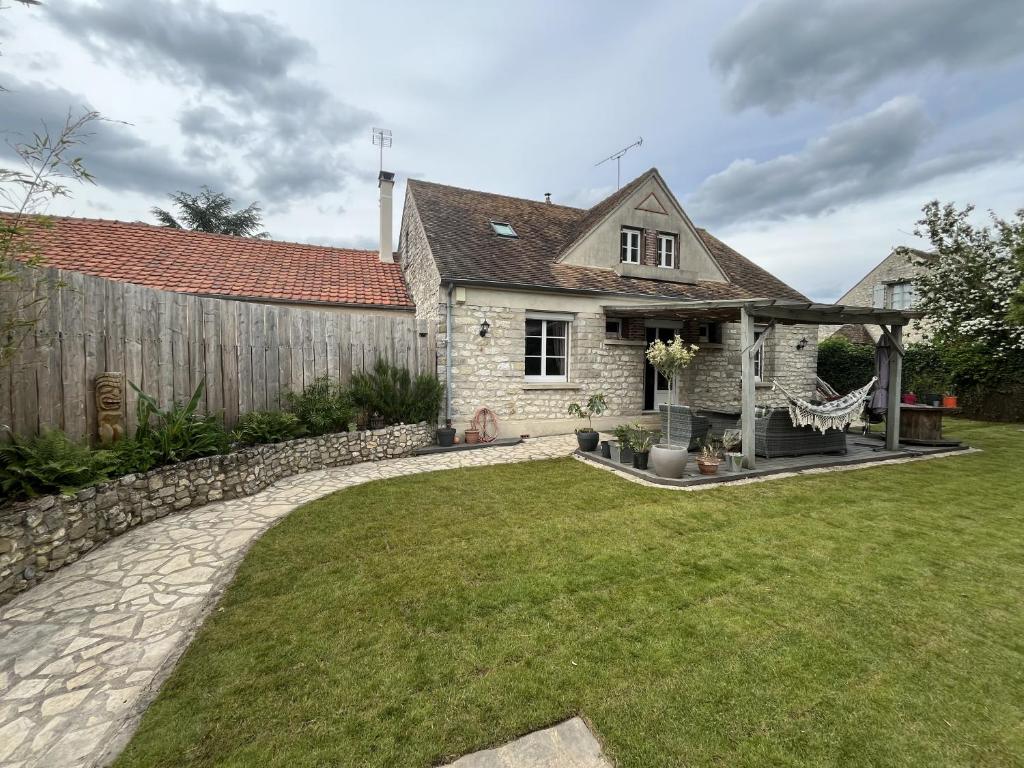 een tuin met een stenen hek en een huis bij Sous le chemin de Paris in Milly-la-Forêt