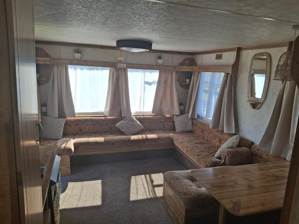 Una sala de estar con un sofá en la parte trasera de un autobús. en Idyllic Family Holiday Caravan, en Skegness