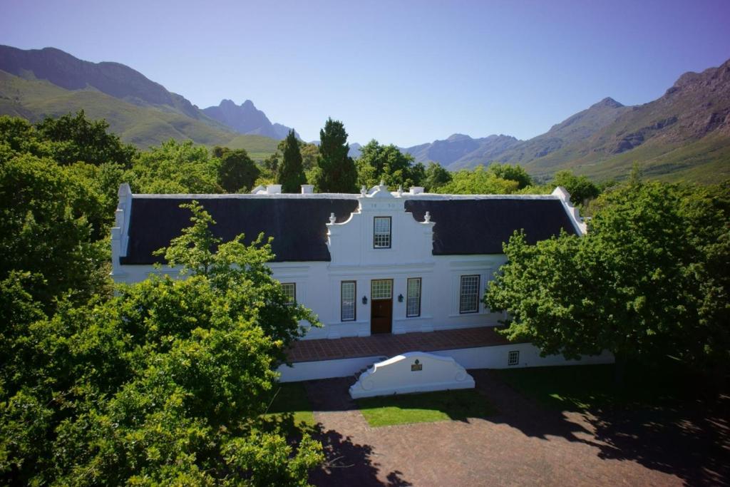 a white house with a blue sky and trees at Lanzerac Hotel & Spa in Stellenbosch