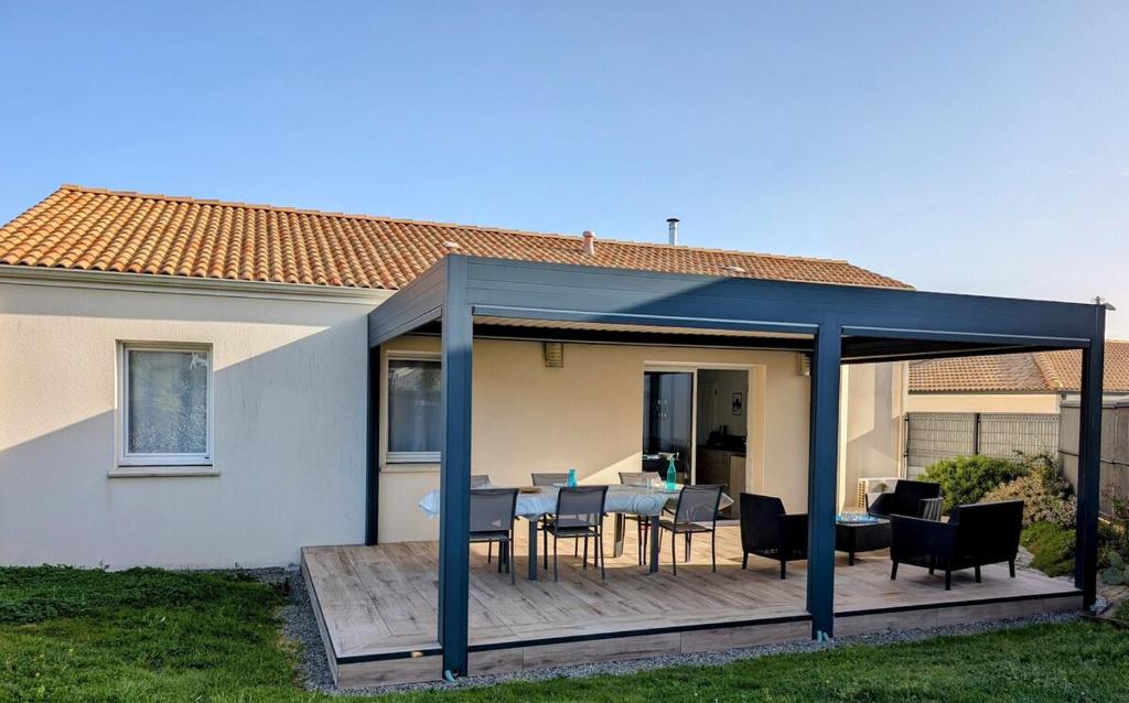einen Pavillon mit einem Tisch und Stühlen auf einer Terrasse in der Unterkunft Les Merisiers - Maison moderne avec jardin in Pornic