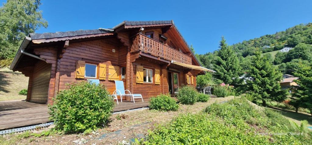 une maison en bois sur une colline avec une terrasse dans l'établissement Le Chalet Du RAINDÉ - Vue Panoramique, à La Bresse