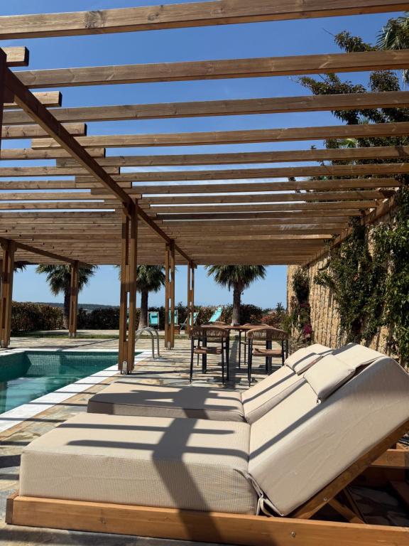 a bed under a wooden pergola next to a pool at SANIMAR By Mono Alex in Kassandra