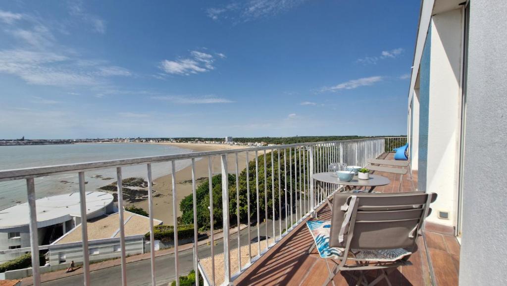 un balcon avec une table et des chaises et une vue sur la plage dans l'établissement Saint Georges de DIdonne - VUE MER PANORAMIQUE pour ce BEL APPARTEMENT, à Saint-Georges-de-Didonne
