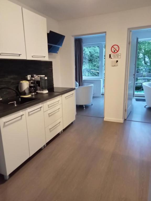 a kitchen with white cabinets and a wooden floor at Willa Aqua -parking included in the price in Świnoujście