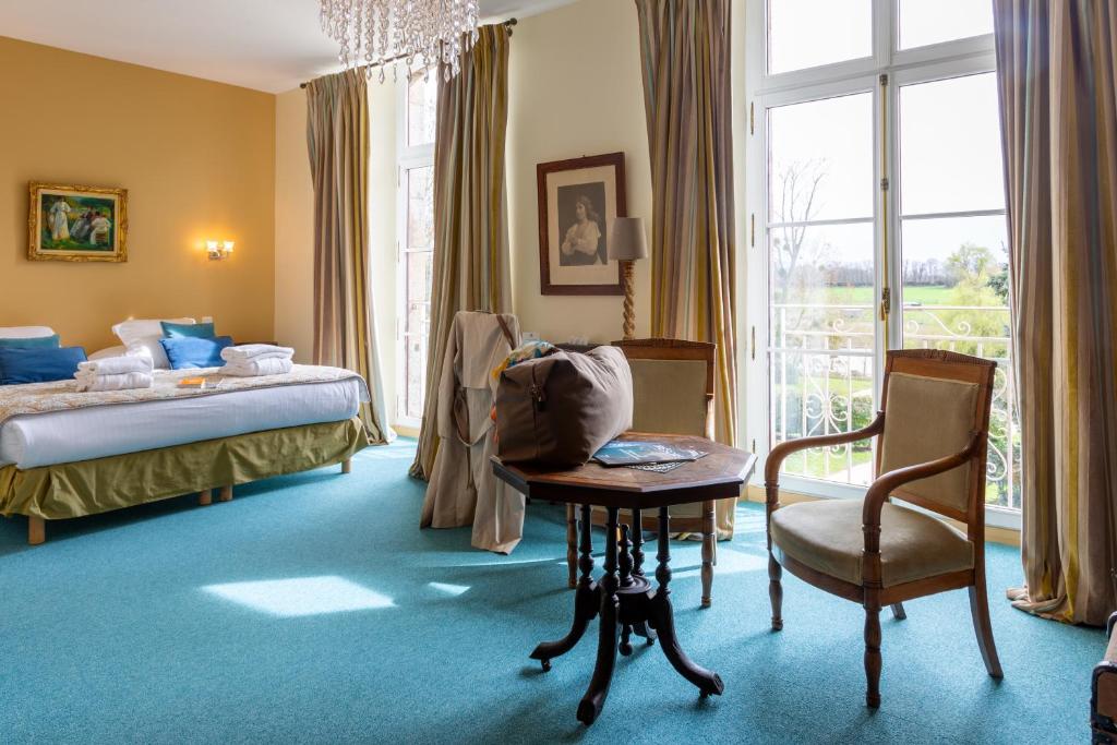 een slaapkamer met een bed, een tafel en een stoel bij Château Hôtel Du Colombier in Saint-Malo