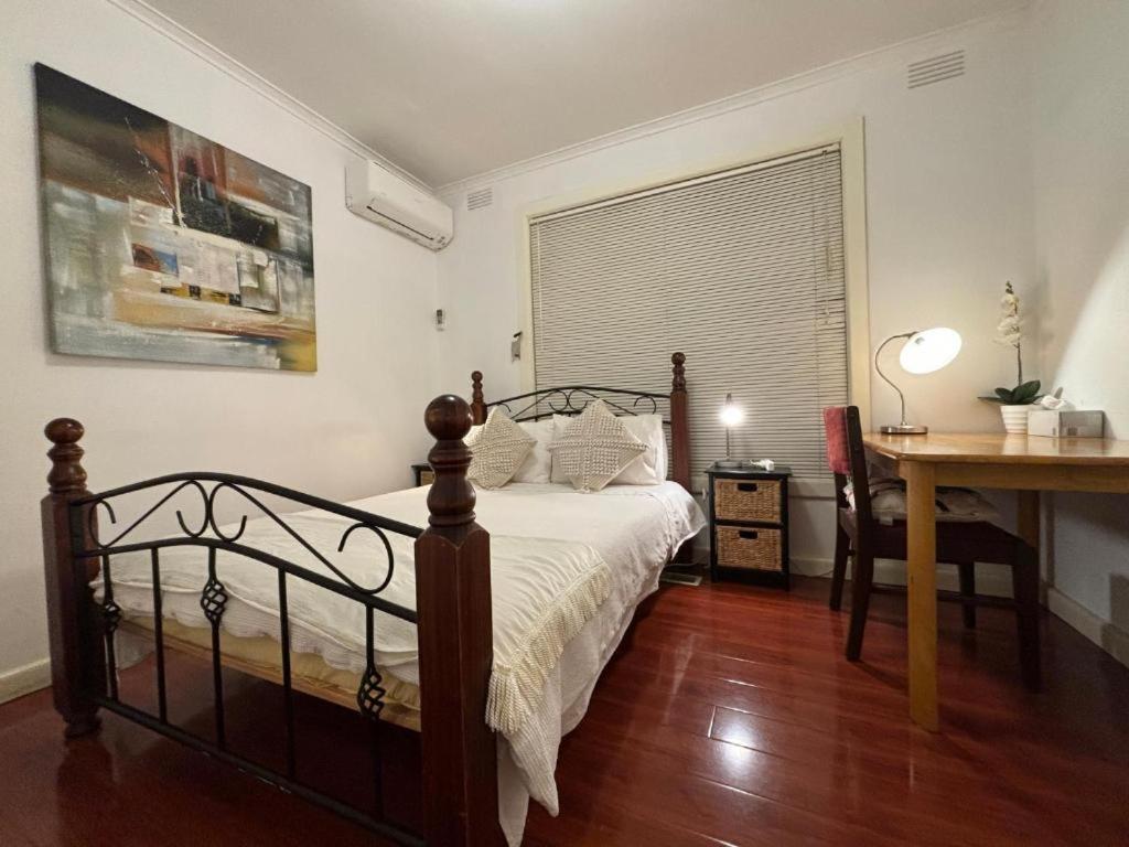 a bedroom with a bed and a desk and a window at Garden Guesthouse - Melbourne Airport Accommodation in Melbourne
