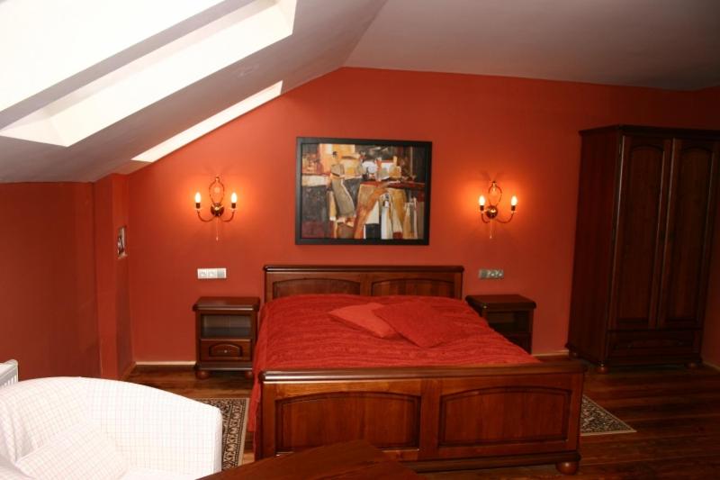 1 dormitorio con paredes rojas y 1 cama con sábanas rojas en Zlaty Lev, en Louny