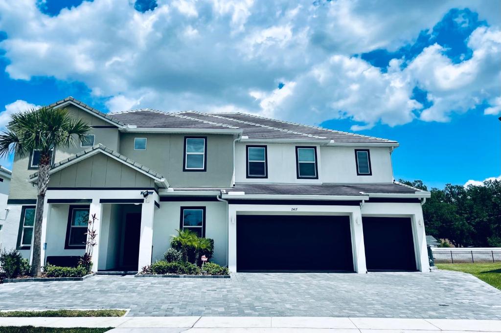 a white house with a large garage at Deluxe themed private ROOMS - Ensuite Bath & Pool Access by Casa Da Jura in Kissimmee