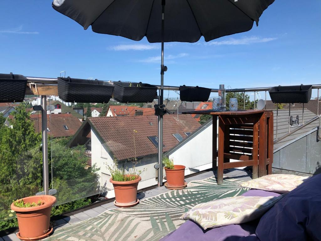 a patio with an umbrella and potted plants on a balcony at 3-room apartment with terrace and carport in Filderstadt in Filderstadt
