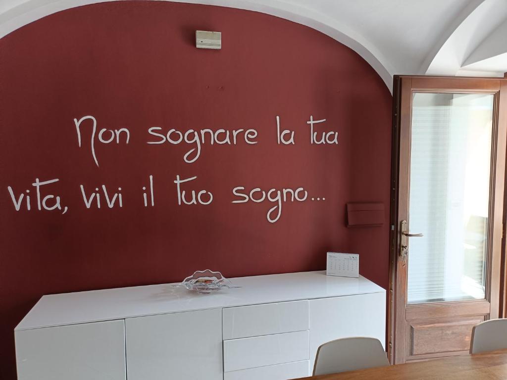 a room with a red wall with writing on the wall at La petite maison Fleur in Biella