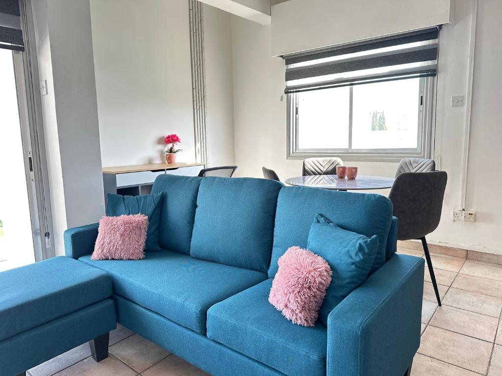 a blue couch with pink pillows in a living room at Adonis Holiday Apt - Nicosia in Nicosia